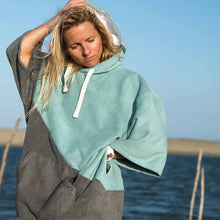 Load image into Gallery viewer, Woman wearing a two-tone gray and teal poncho by the ocean
